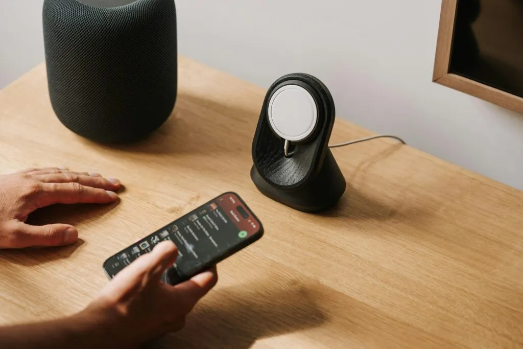 A modern desk setup featuring tech gadgets with a smartphone and smart speaker.