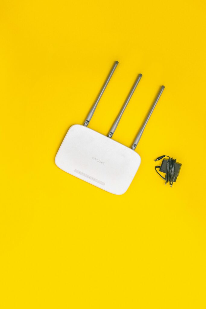 White router with three antennas and cables on bold yellow background, ideal for tech concepts.
