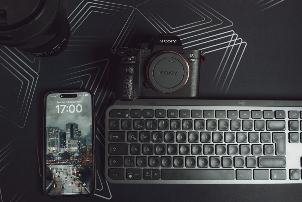 Elegant workspace setup featuring camera, smartphone, and keyboard on a geometric background.